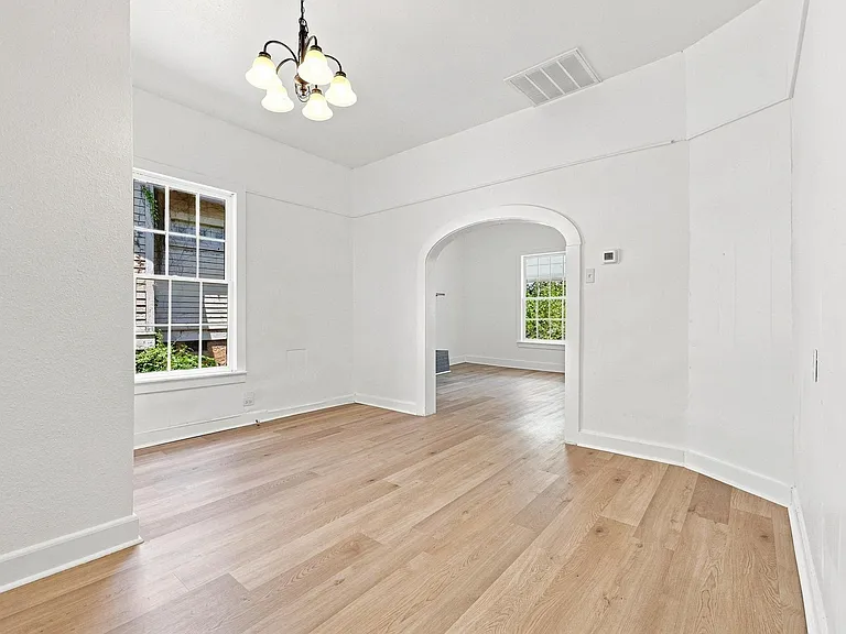 Dining room featuring light wood-finish flooring, crisp white walls, and a five-light chandelier