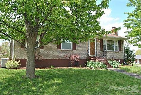 Large mature trees offer shade for this manicured lawn