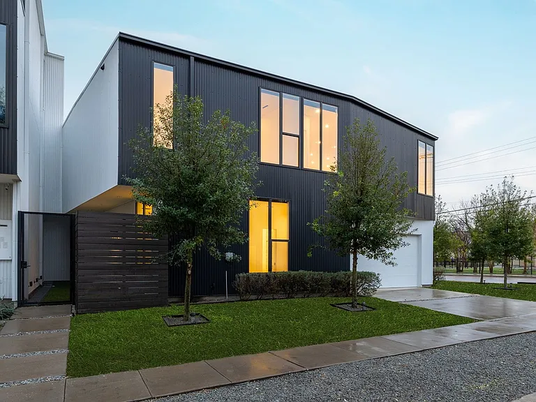 Modern architectural residence featuring a dark corrugated metal facade and white stucco accents