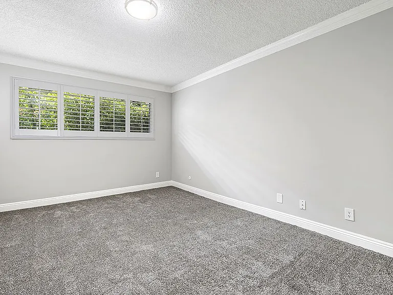 Carpeted bedroom with crown moulding and large exterior windows.