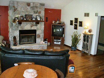 Lots of natural light in this living room with wood/gas fireplace and hardwood