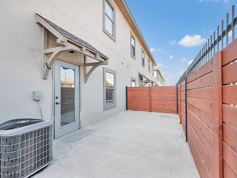 Interior courtyard of Merida Vista Apartments in Laredo, Texas, with a fence and an air conditioning unit visible