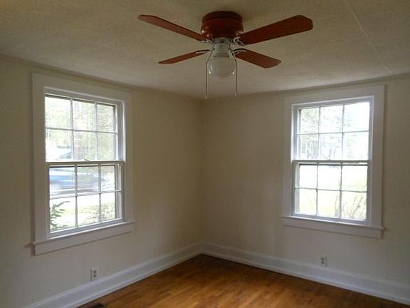 Living Room (Front door is to right, outside of image frame. Window on left looks onto street. Window on right looks into a redbud tree.)