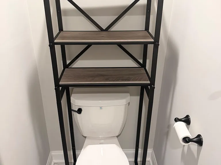 Bathroom toilet nook with an over-toilet shelving unit offering convenient storage for towels and essentials.