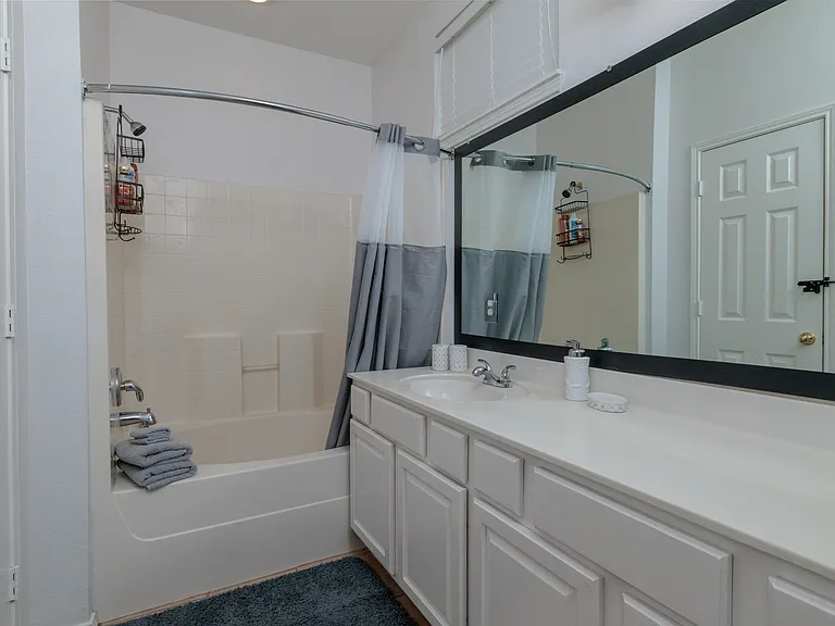 Attached Primary bathroom with bathtub/shower combo with large mirror and sink.