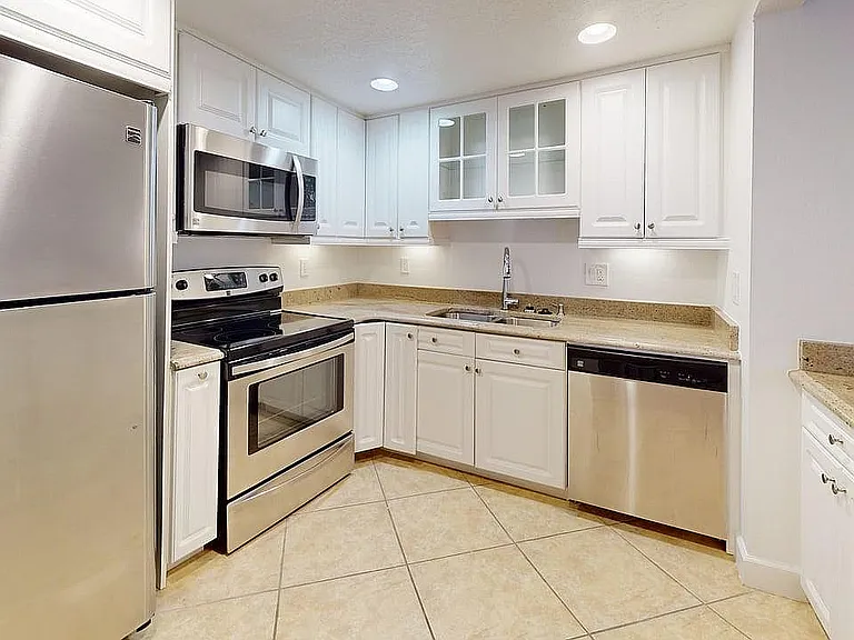 Modern kitchen boasting sleek stainless steel appliances, elegant white cabinetry, and chic granite countertops.