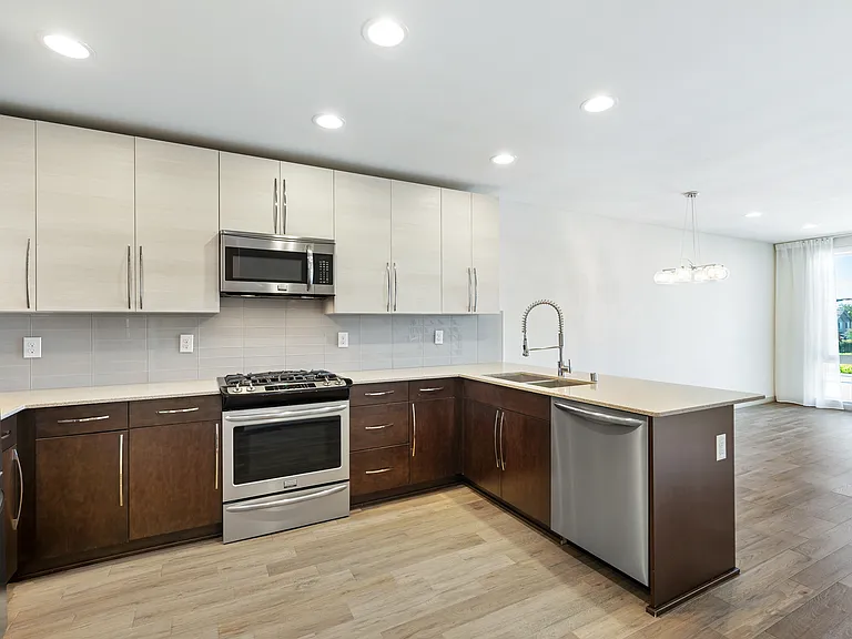 Open concept kitchen with stainless steel appliances, gas stove, full height backsplash.