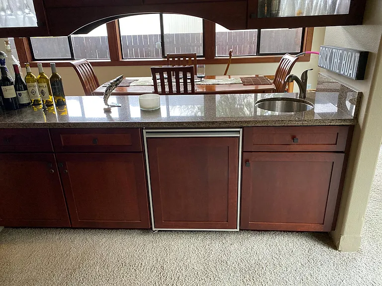 Custom bar/buffet with sink, Sub-Zero refrigerator/freezer with granite counters, under-counter lighting. Custom glass in uppers.
