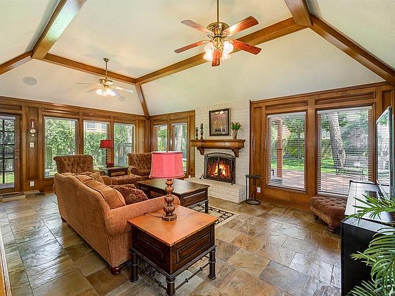 Family room boasts gorgeous wood beams, surround sound, 2 ceiling fans, fireplace with brick surround and stunning slate floor.