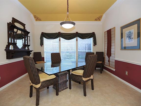 The vaulted ceiling in the dining room is accented with crown molding and tile flooring.