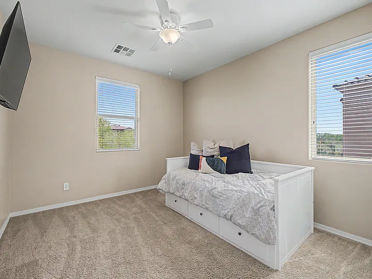 The spacious secondary upstairs bedroom features a mounted TV, generous closet space, and a beautiful view overlooking the pool.