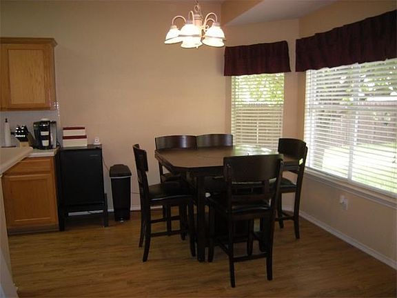 Bay window offers view of tree shaded back yard from dining area