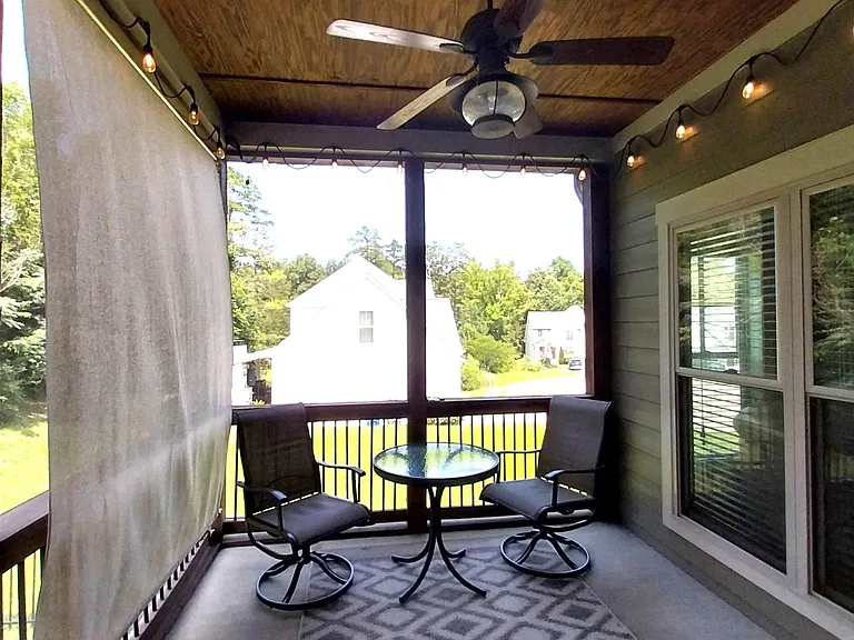 Screened back porch with outdoor table set and beautiful lighting for night setting.