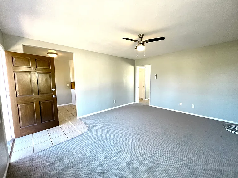 Living room looking towards entry and open eat-in kitchen. Bedroom door at the rear of the room.