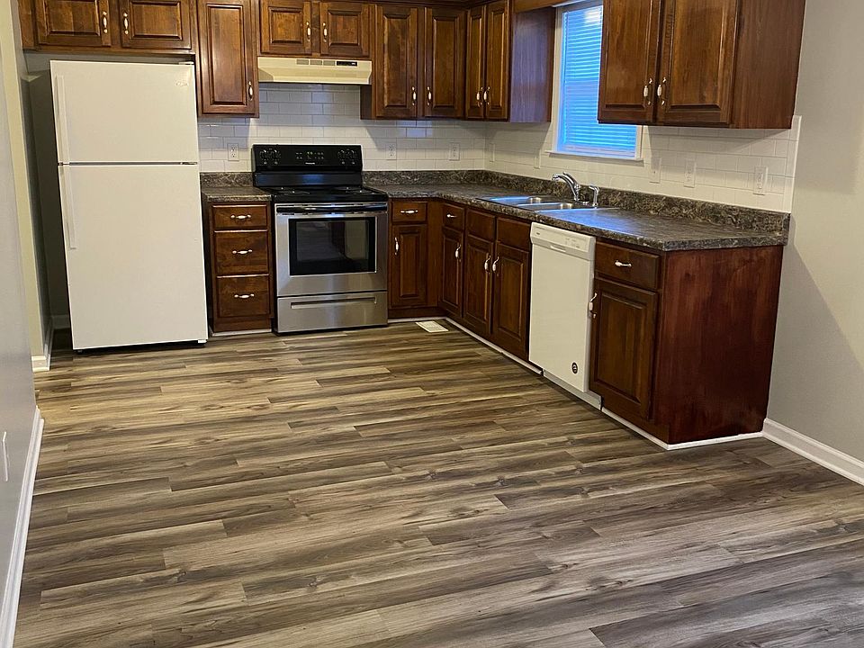 Kitchen includes all appliances, subway tile backsplash, and wood flooring