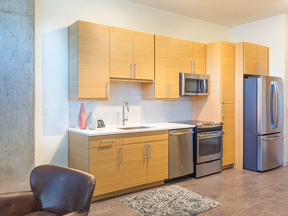 Modern kitchens outfitted with stainless steel appliances, and quartz countertops with tile backsplashes.
