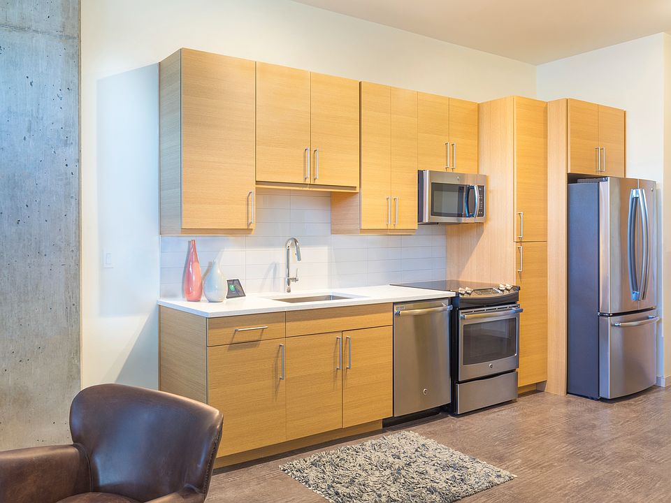 Modern kitchens outfitted with stainless steel appliances, and quartz countertops with tile backsplashes.