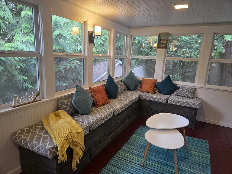 A serene and inviting sunroom designed for year-round enjoyment. Expansive windows blur the lines between indoors and out, creating a bright and airy space perfect for quiet lounging, lively game nights, or intimate meals bathed in natural light