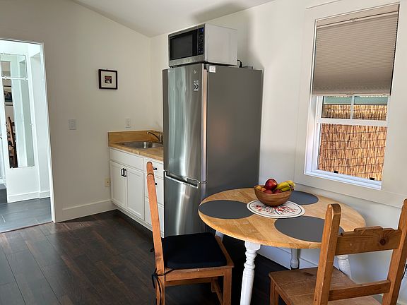 The kitchen and the seating area. The microwave sits on top of the fridge. The refrigerator is about 3 years old and has plenty of space for food storage.