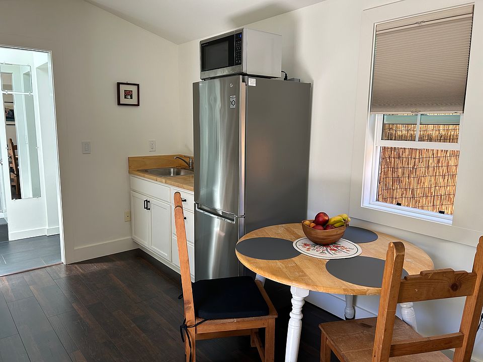 The kitchen and the seating area. The microwave sits on top of the fridge. The refrigerator is about 3 years old and has plenty of space for food storage.