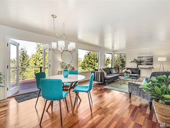 Huge oversized living and dining area with Brazilian Cherry(Jatoba) hardwood flooring and a wall of western facing windows overlooking the home's private parklike forested lot.