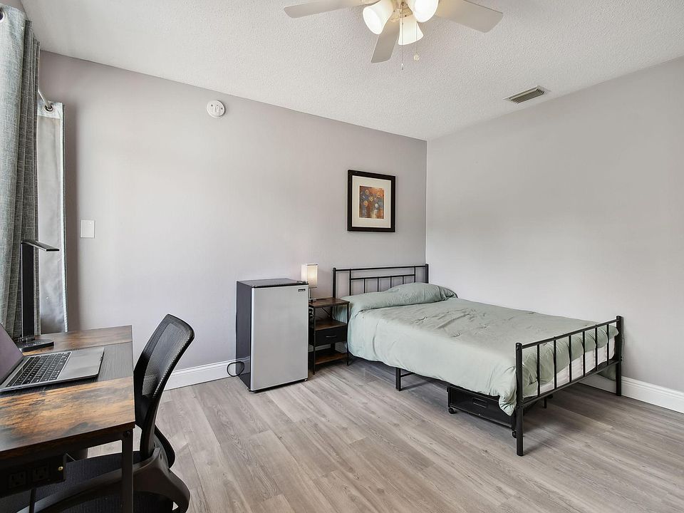 Full size cozy bed, with end table, light, office desk, chair and light as well as storage container under the bed.