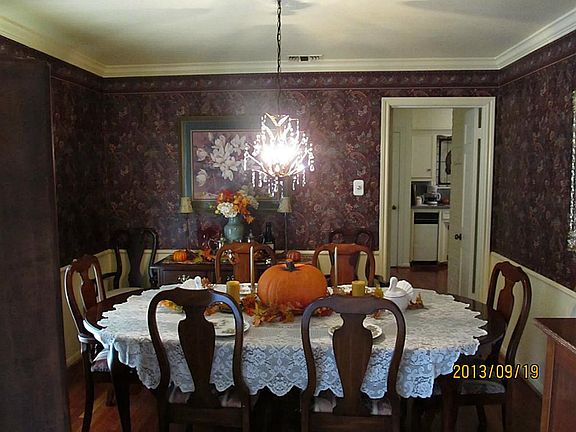 Large dining room features chandelier and wood floors.