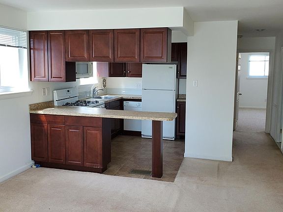 View of kitchen from living room showing island and hallway to bedrooms.
