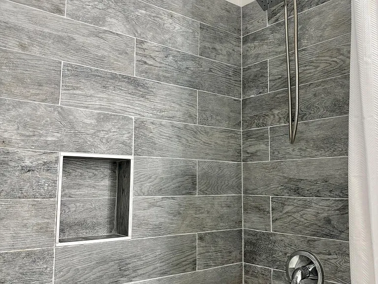 Room 1 - Tiled tub/shower surround with built-in niche shelving and a rain-style showerhead for everyday convenience.