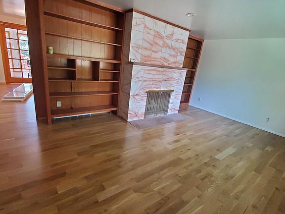 Living room with rose marble fireplace and hard wood floors.