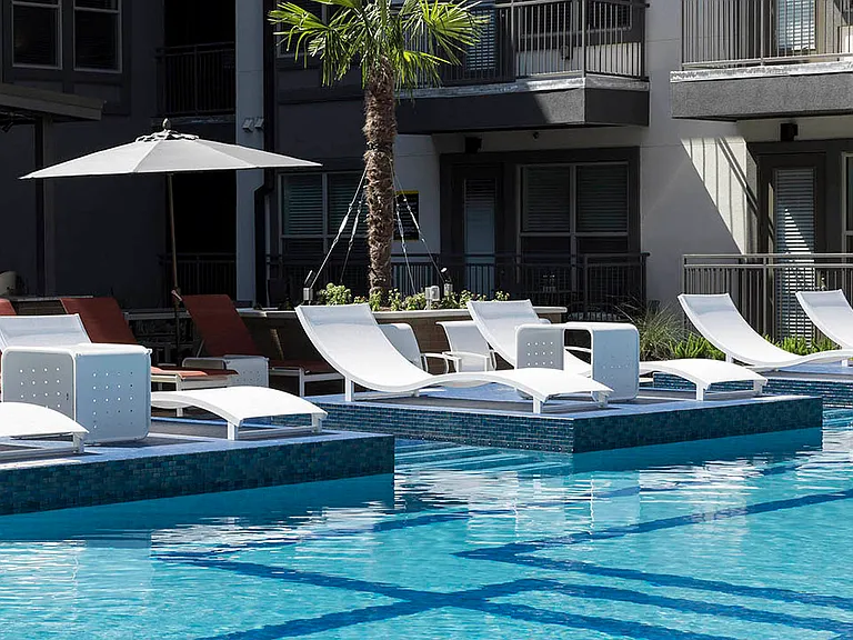 Resort-style pool with lounge chairs and gazebos.