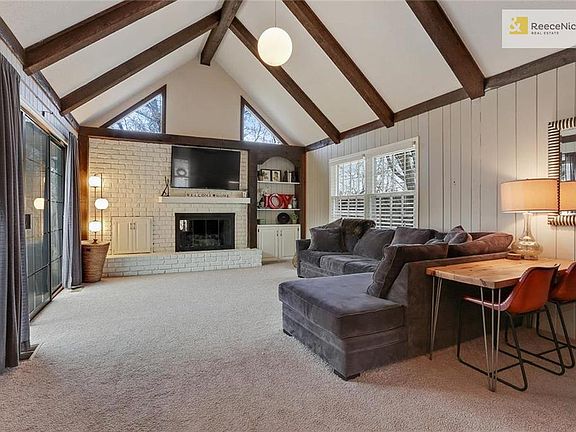 Charming family room is even better with its brick fireplace, built-ins, and exposed wood beams.