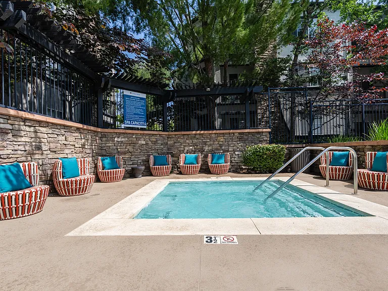 Resident Hot Tub Area with Lounge Chairs and Stone Wall Backdrop