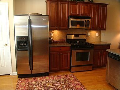 Kitchen has richly stained cabinets, S/S applicances, Corian counters, Pantry!