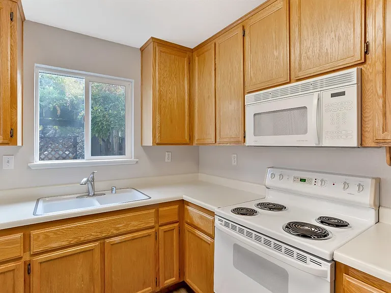 The close view into the kitchen's sink, stove, & microwave.