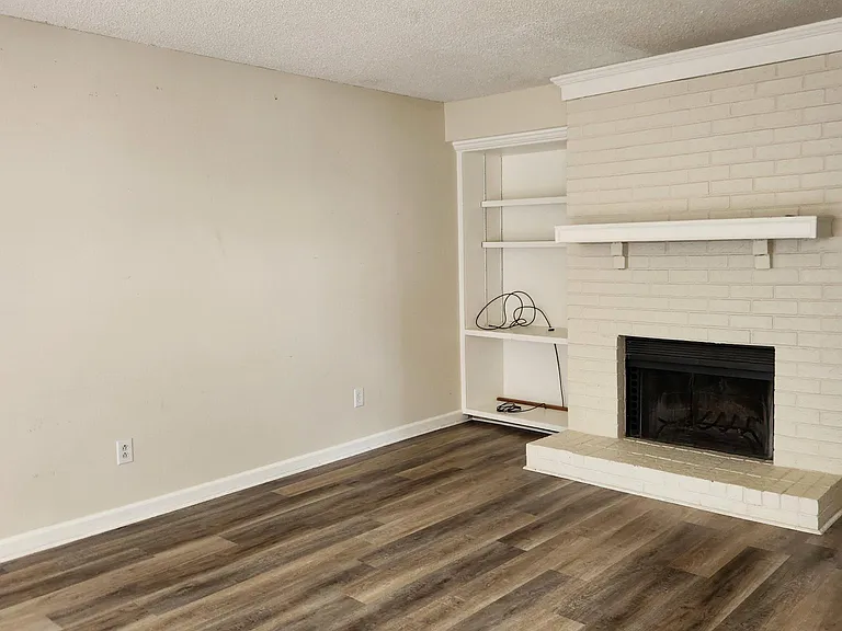 Large living room has a fireplace, bay windows, and built-in shelving.