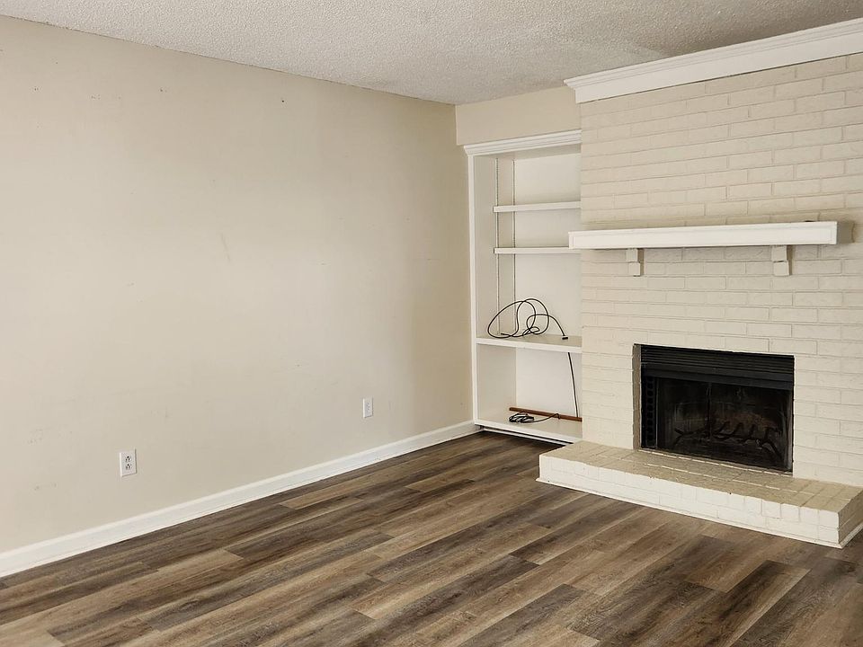Large living room has a fireplace, bay windows, and built-in shelving.