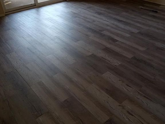 Living room with new flooring. Sliding glass door to front facing deck and storage area.