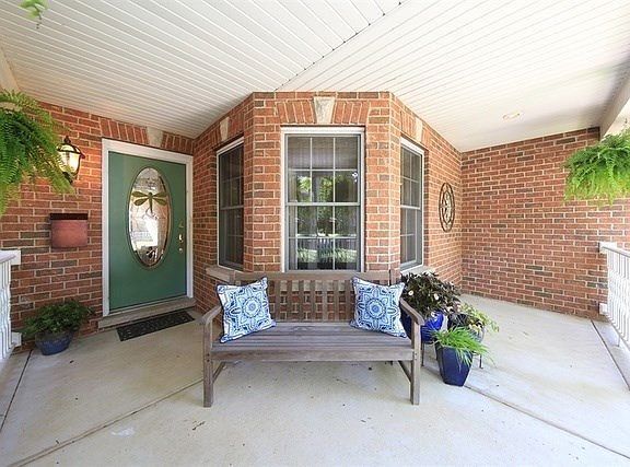 Covered porch entry with views of professional landscaping.