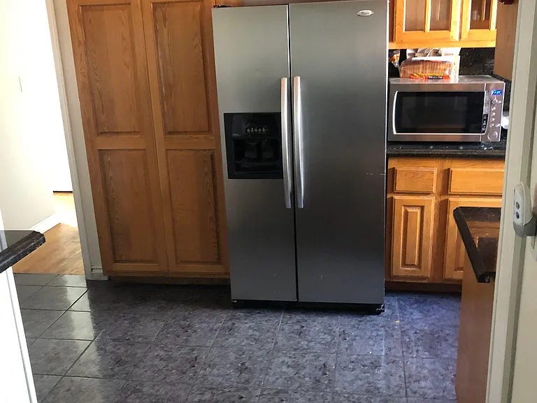 Kitchen features generous wood cabinetry, a side-by-side refrigerator, and durable counters with space for small appliances.