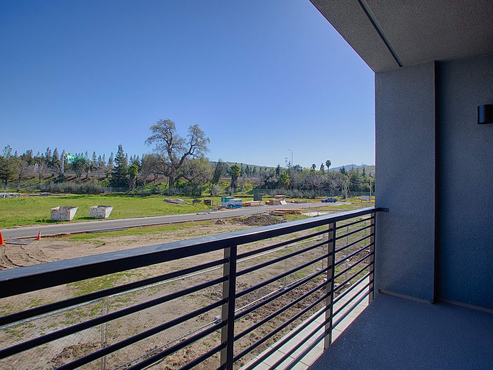 The image shows a scenic outdoor view from a balcony or porch, with a grassy field in the foreground