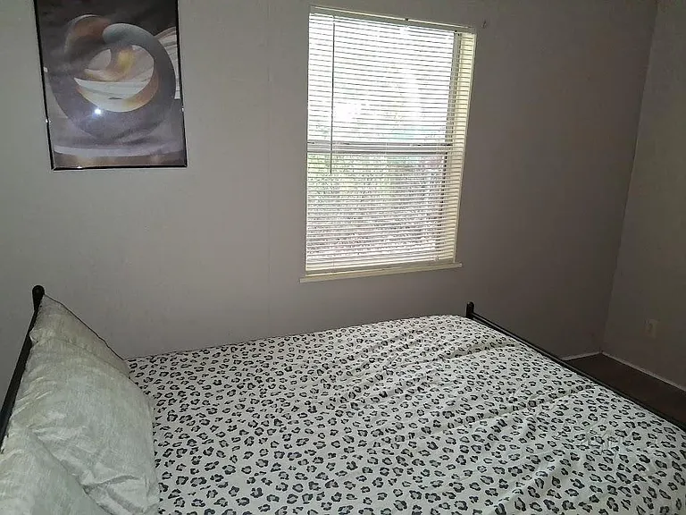 Private bedroom with a furnished bed setup, window blinds for light control, and neutral walls for easy personalization.