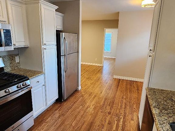 Kitchen with white cabinets, granite counters and backsplash
