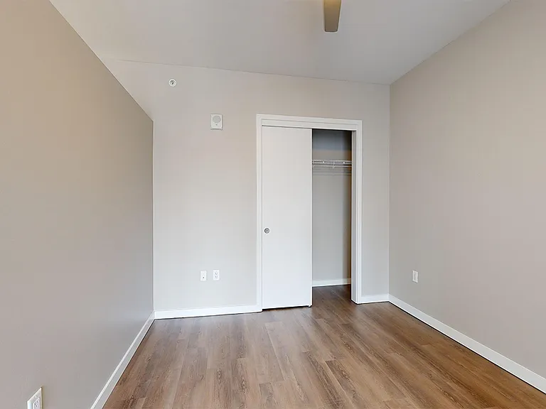 Spacious apartment bedroom with wood-style flooring.