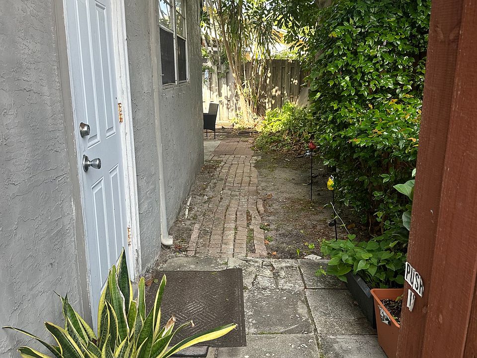 The entrance is located on the right side of the property through a wooden gate.