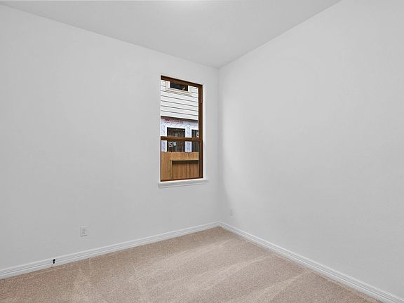 A comfortable third bedroom with plush carpet, a sun-filled window, and ample closet space.