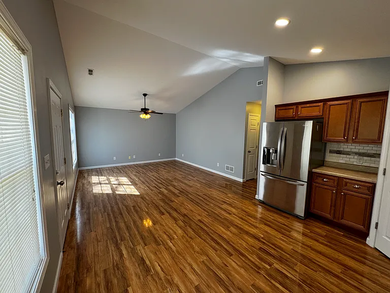 Beautiful kitchen and living room with elegant hardwood floor and a beautiful stainless steel refrigerator that dispenses water and ice for your convenience.