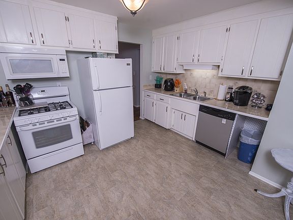 Complete with updated flooring, light fixtures, and hardware, the kitchen (12x11) features lovely tile countertops and backsplash, a five burner gas range, dishwasher, and gleaming white cabinets.  