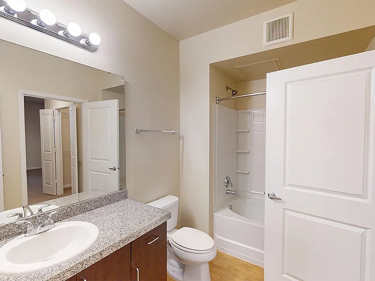 Apartment bathroom with large soaking tub and wood-style flooring.