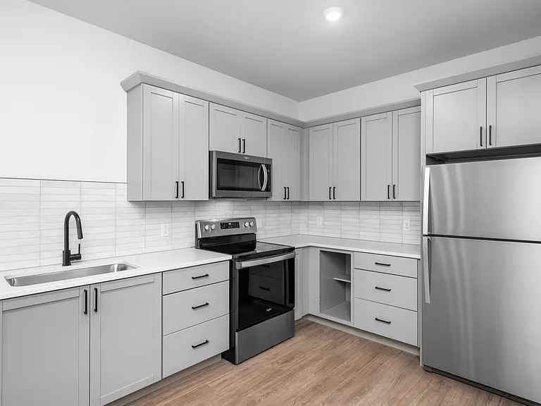 Modern kitchen with sleek gray cabinetry, stainless steel appliances, and elegant wood flooring. Modern kitchen with sleek gray cabinetry, stainless steel appliances, and elegant wood flooring.